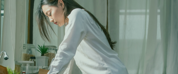 Woman leaning over counter looking down thinking.
