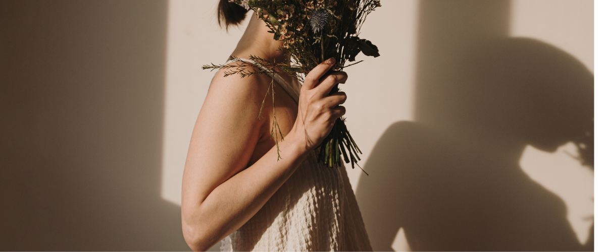 Woman holding a bunch of wildflowers in front of her shadow.
