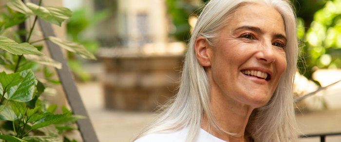 Middle aged woman with grey hair smiling.