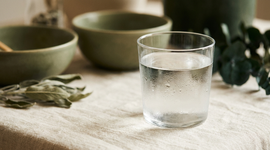 A clear glass of still water with condensation on cream linen